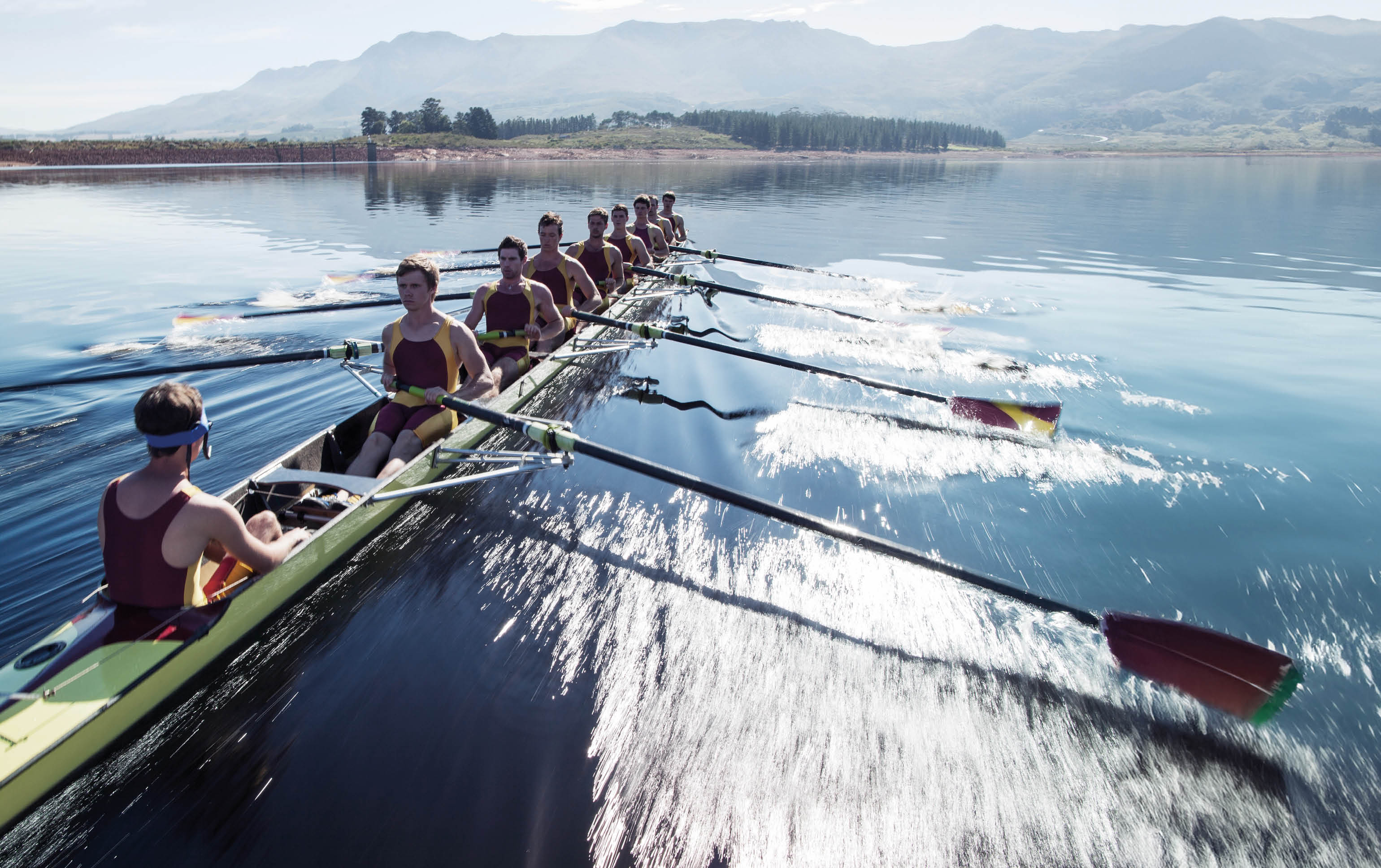 Rowing team rowing scull on lake